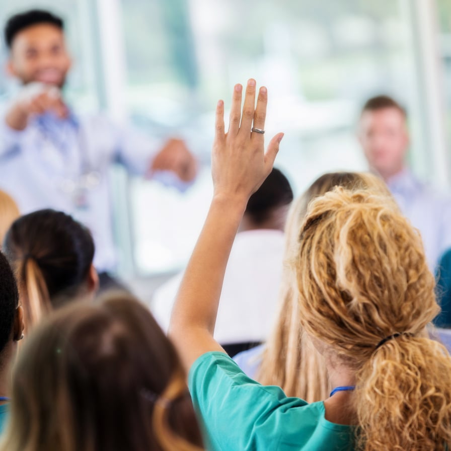 Unrecognizable healthcare professional raises hand during conference